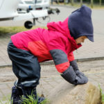 Kind mit Vaude 3 in 1 Jacke klettert auf einen Stein